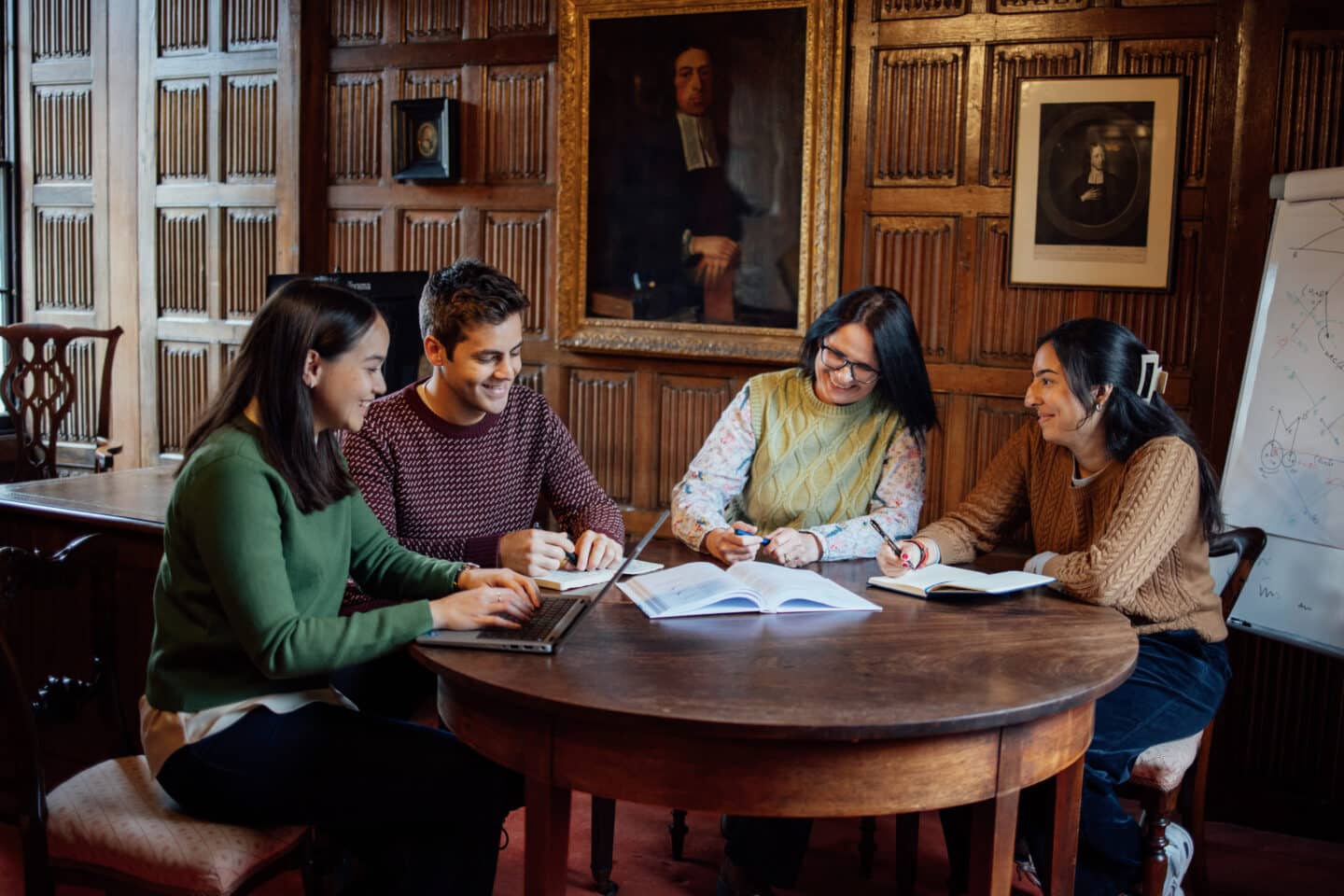 Four students revising around a wood table in the Wesley Room
