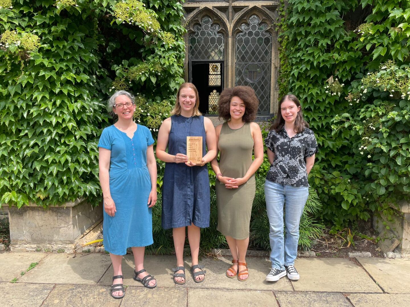 Members of Lincoln College’s Green Impact Team standing together in front of a historic ivy-covered window, smiling and holding their 2024–25 Beyond Gold award from the University of Oxford’s Green Impact scheme.