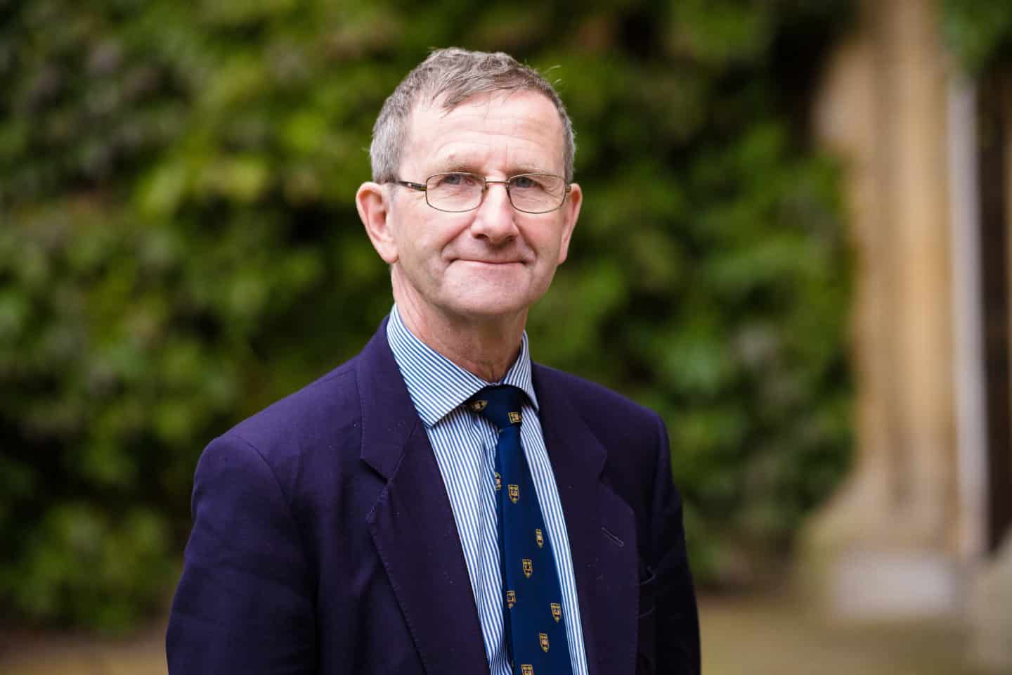 Headshot of Professor David Hills, a man in glasses and a suit and tie