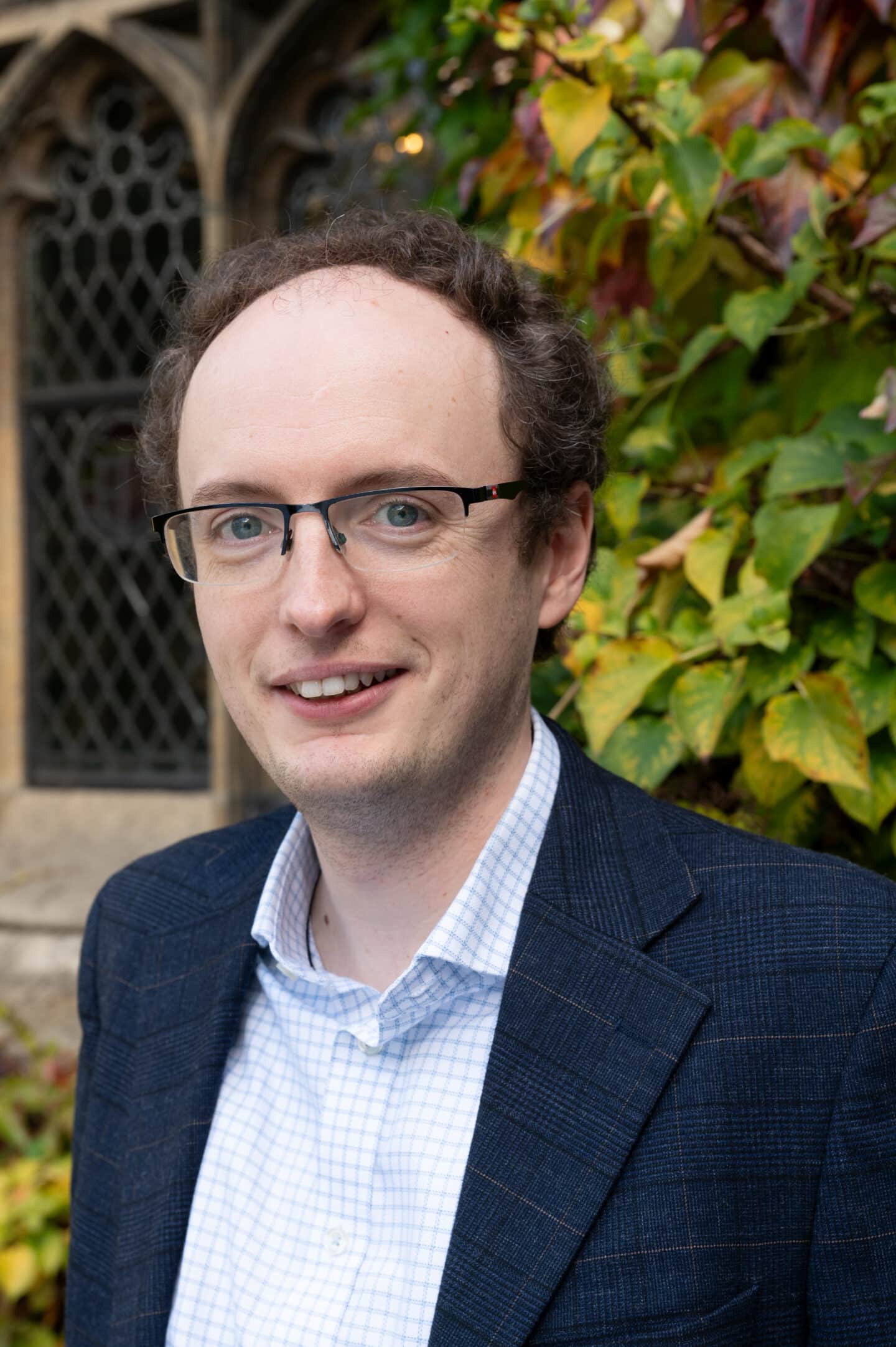 Fred Smith standing in Front Quad at Lincoln College, Oxford, with ivy and stonework visible behind.