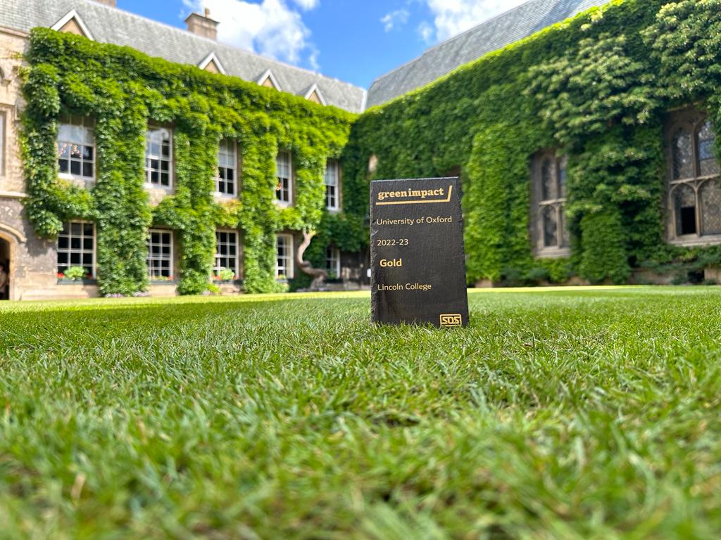 GOLD Green Impact Award propped upright on grass in Front Quad