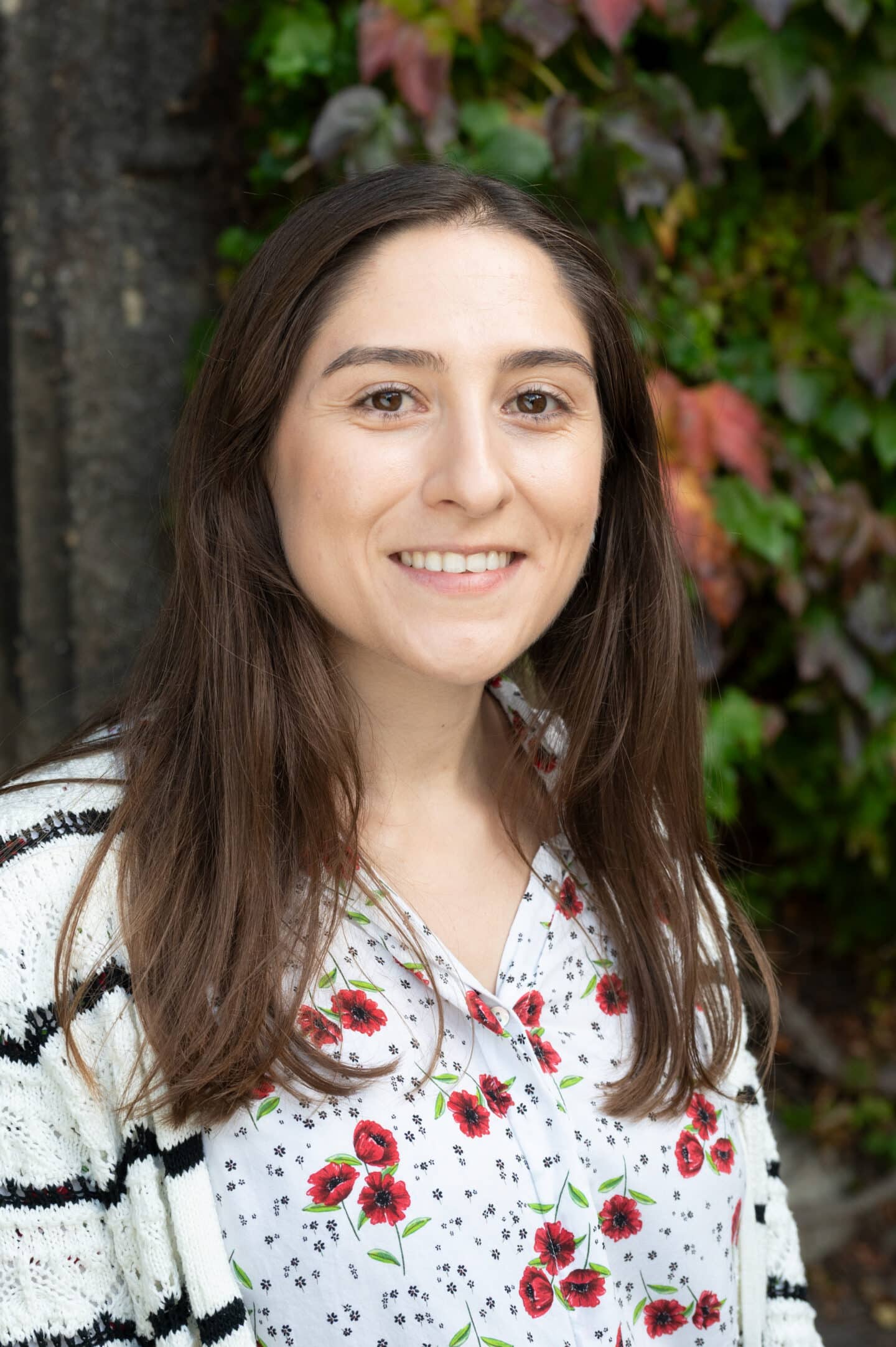 Ines Díaz del Olmo standing in Front Quad at Lincoln College, Oxford, with green and red ivy in the background.
