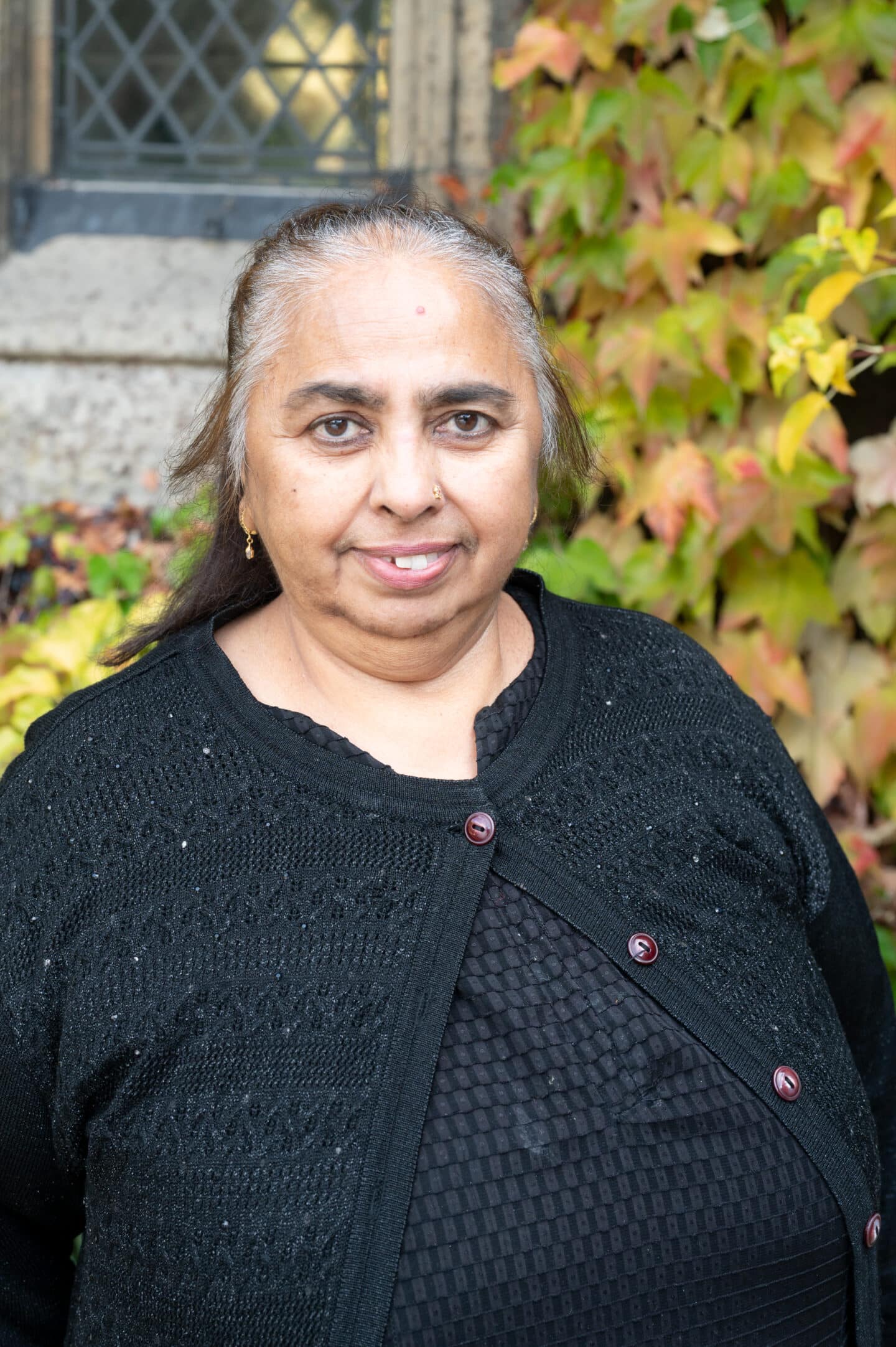 Katie Ali standing in Front Quad at Lincoln College, Oxford, in front of ivy-covered stonework.