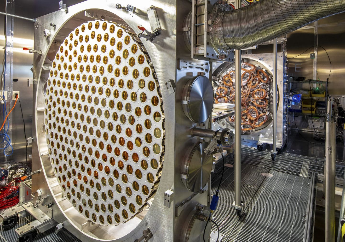 Large detector component filled with dozens of gold-coloured photosensors, with cables and additional scientific equipment visible in the background.