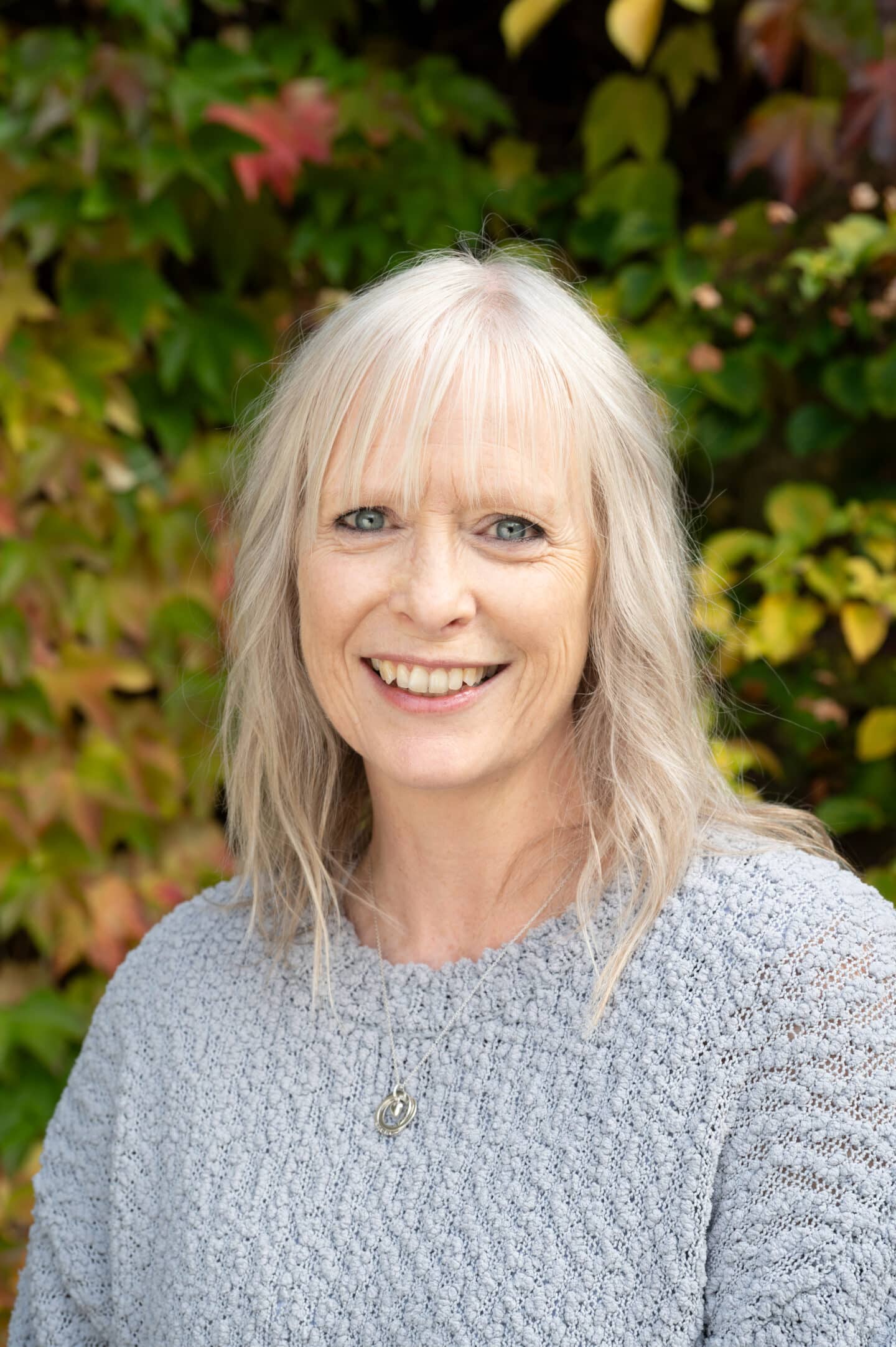 Rachel King standing in Front Quad at Lincoln College, Oxford, smiling with green and red ivy behind.