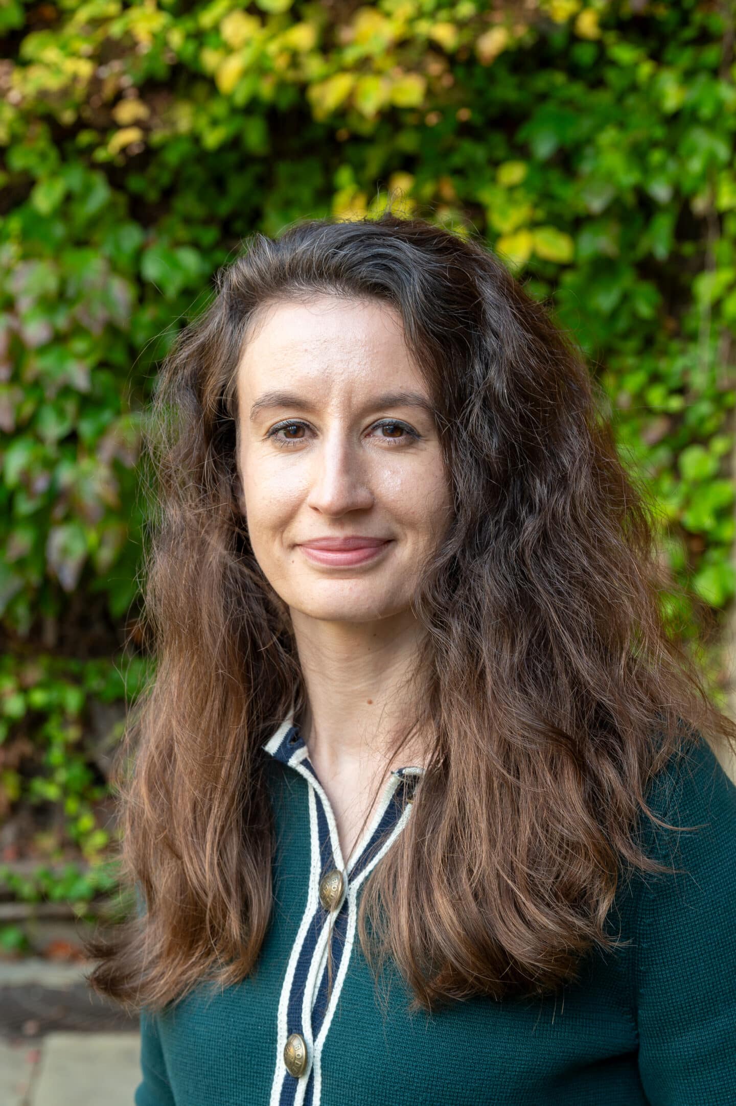 Lucy Langton standing in Front Quad at Lincoln College, Oxford, with green ivy on the wall behind.