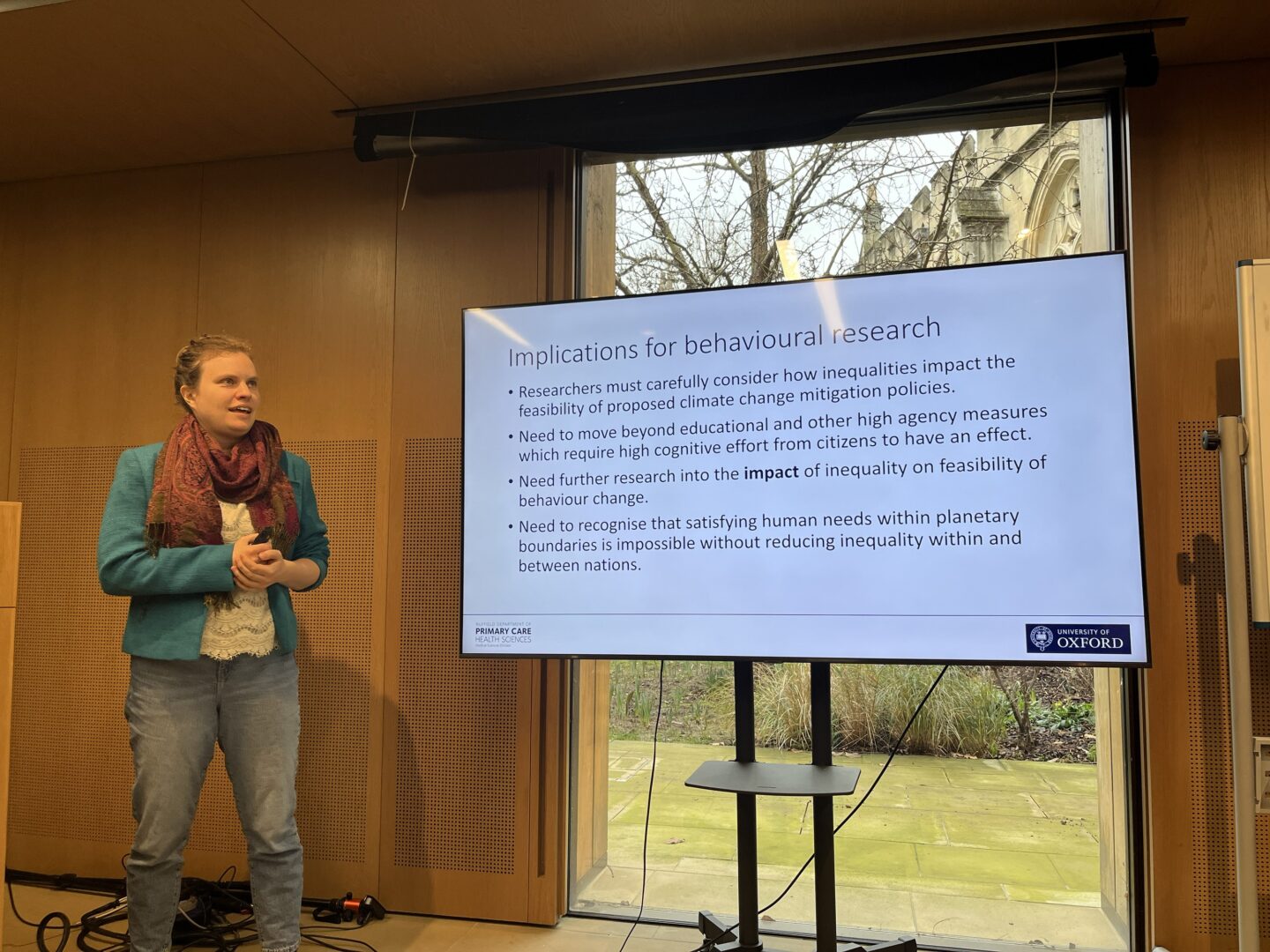 Dr Emma Garnett resents a slide titled “Implications for behavioural research” during a Green Impact lunchtime seminar at Lincoln College. The presentation discusses the role of inequality in climate change mitigation and the need for inclusive behavioural approaches.