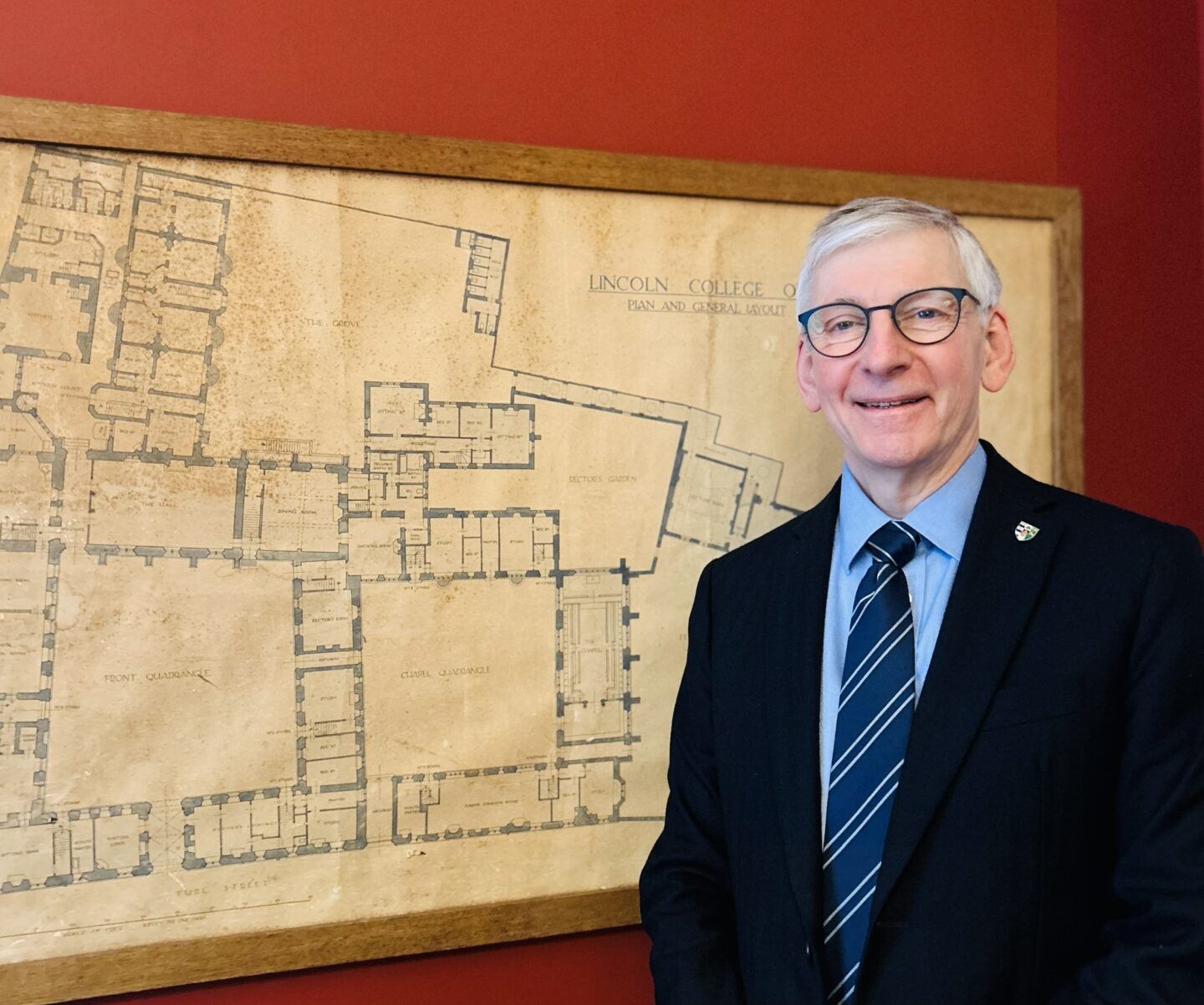 Nigel Clifford standing next to a yellowed wall map of Lincoln