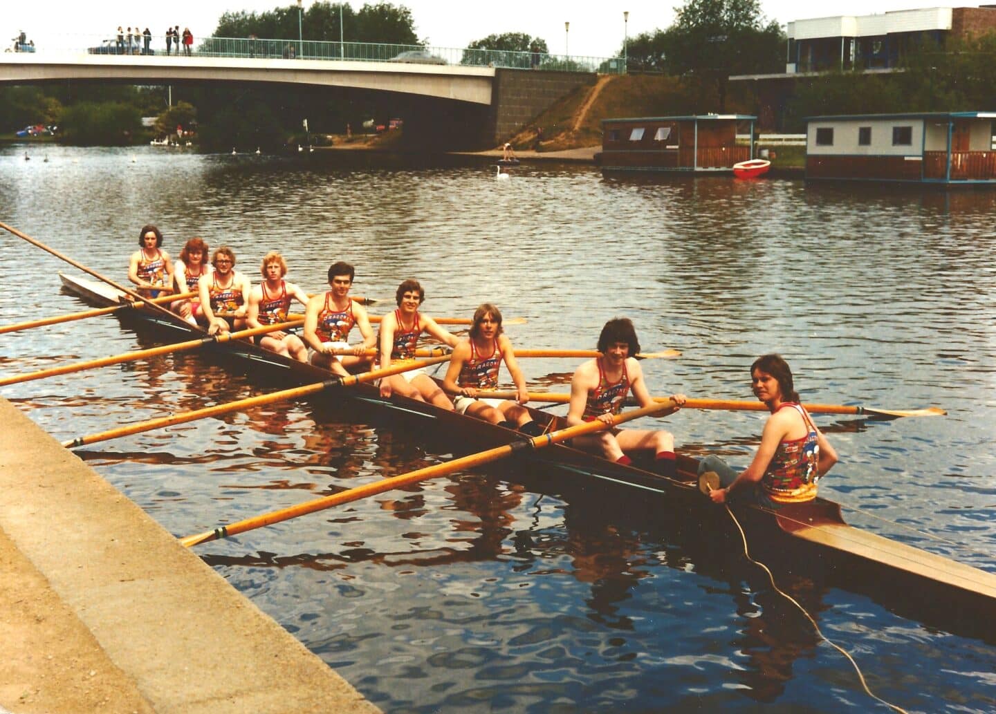 One of Lincoln’s Lower VIIIs at Summer VIIIs, c. 1975: One of Lincoln College's lower boats sits alongside the bank before racing at Summer Eights, circa 1975.