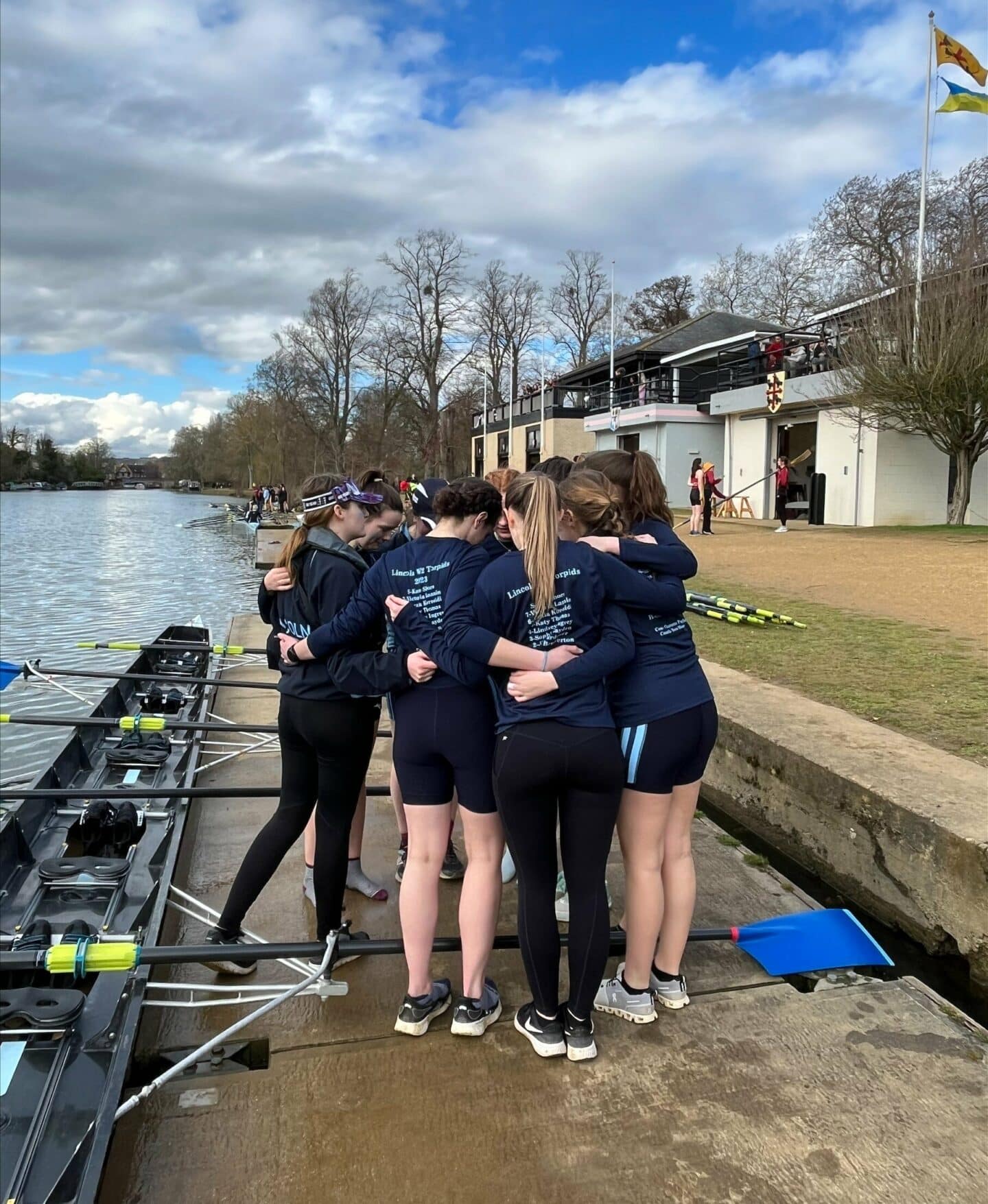 Group of Lincoln W2 rowers huddling by the river