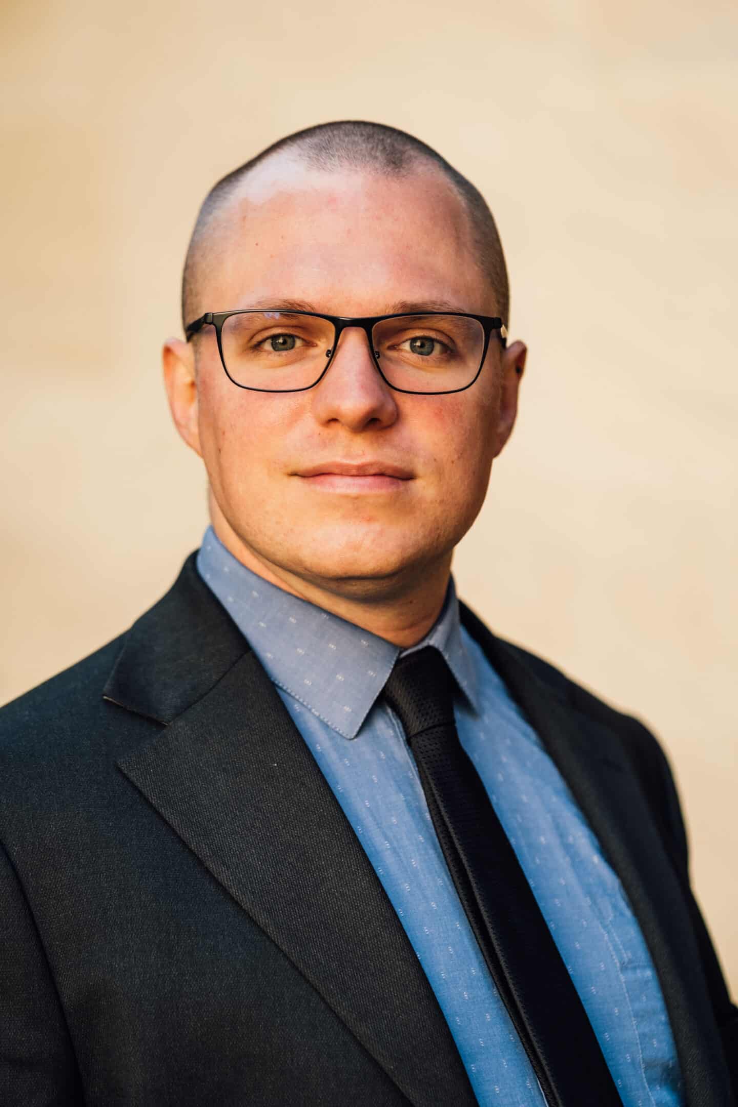 Headshot of Andrea Pasqualini, a man in a suit and tie, with glasses