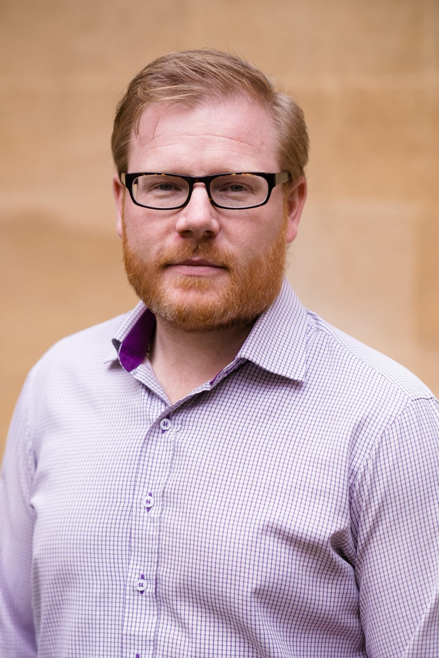 Headshot of Andrew Miller, a man in a white and purple checked shirt