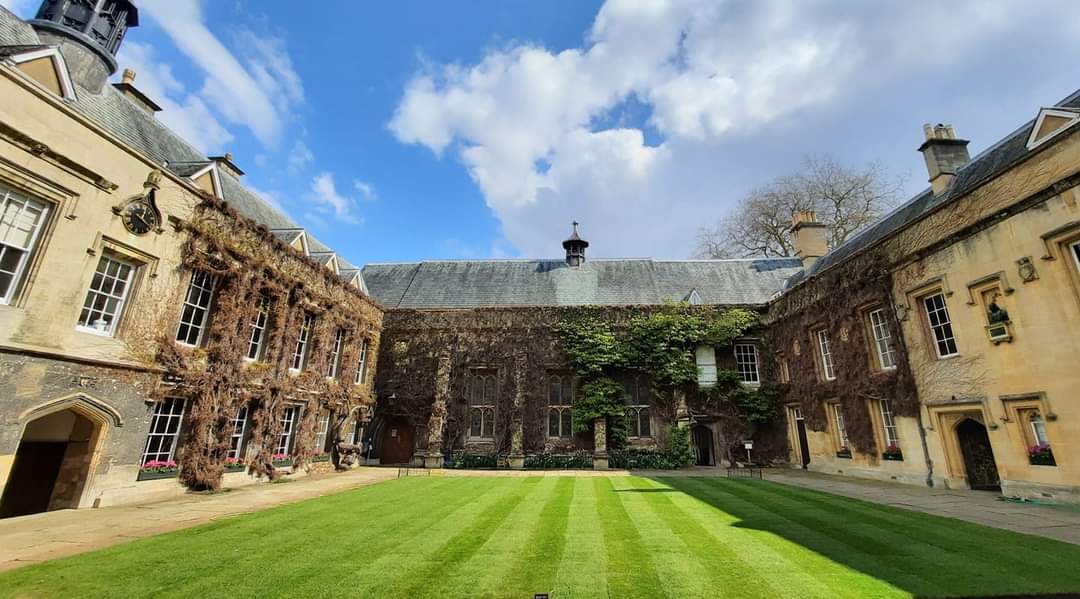 The Front Quad of Lincoln College, with brown ivy covering the walls, but the lawn green