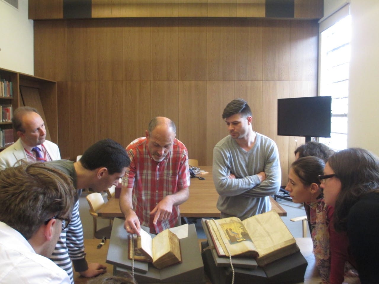 Photograph from a Greek summer school of a group looking at a couple of open manuscripts