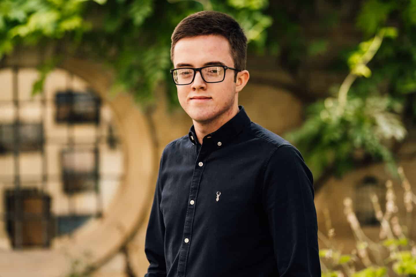 Headshot of Jamie Butler, a man in a dark shirt and glasses