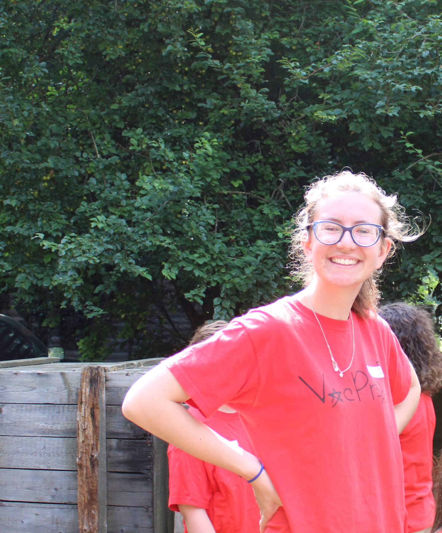 Headshot of Lara Hatwell, a young woman in glasses and a red 'Vac Proj' t-shirt