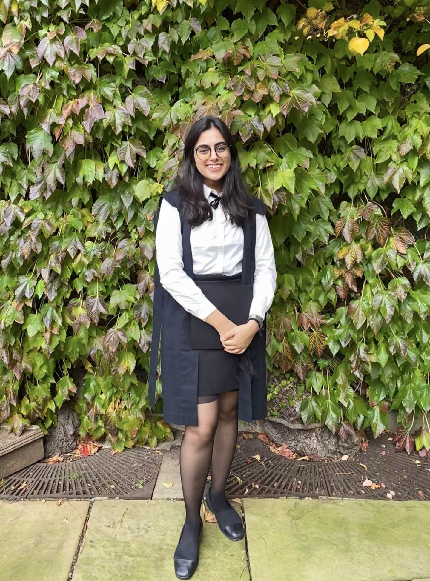 Photograph of Lavanya Singh, a young woman in subfusc, holding a mortarboard.