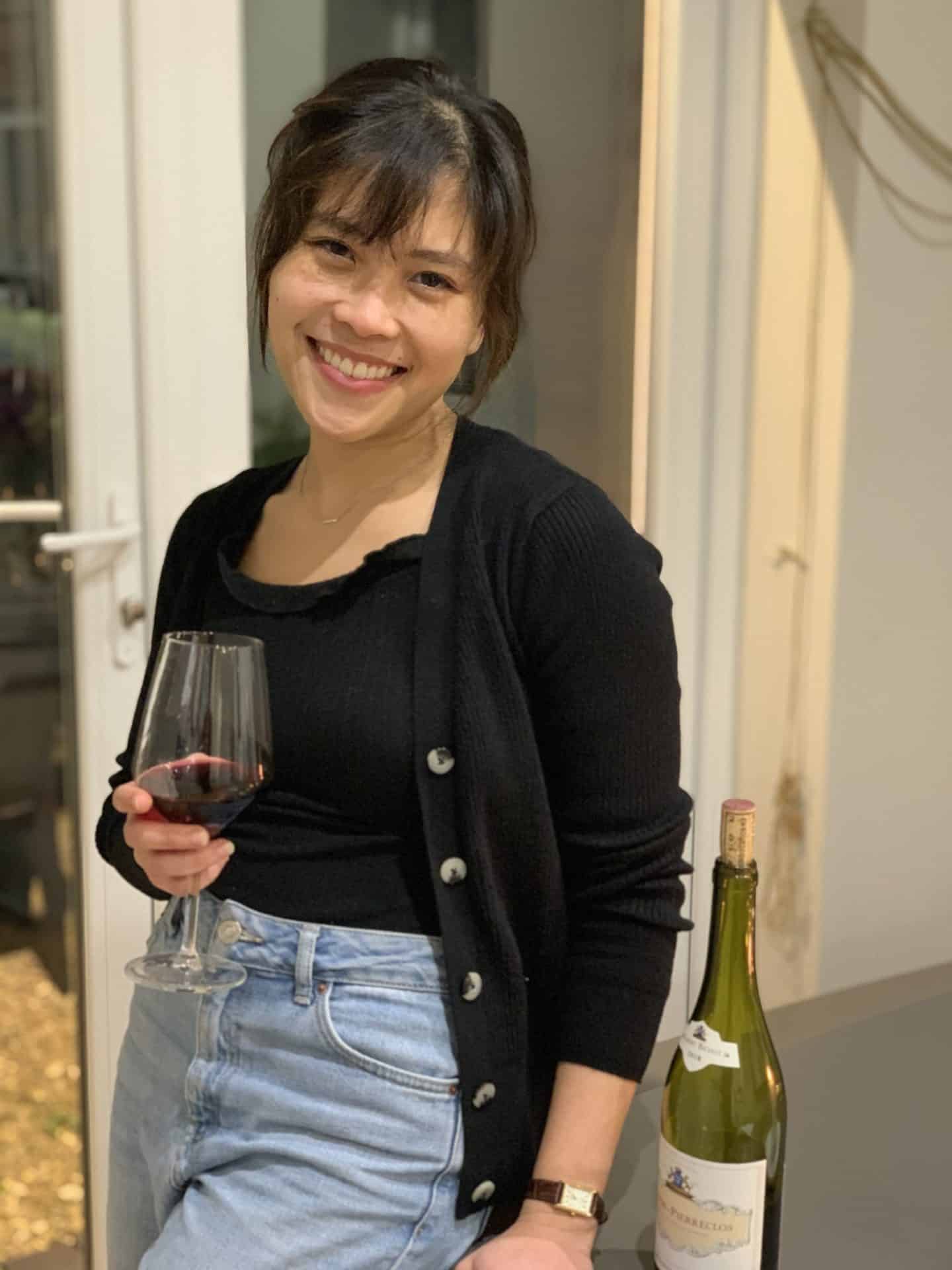 Photograph of Micon Garvilles, a young woman in a black cardigan holding a glass of red wine