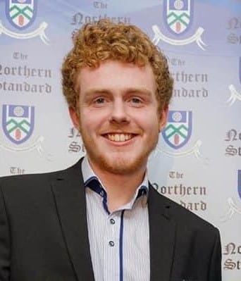 Headshot of Patrick Duffy, a smiling young man in a suit, with logos of the Northern Standard in the background