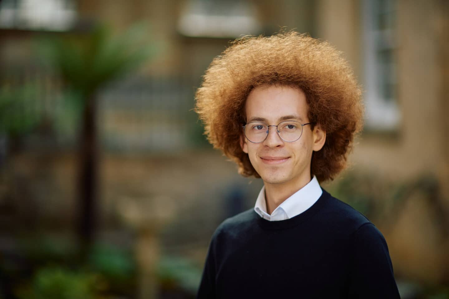 Headshot of Peter Nitsche Whitfield, a man with red hair, glasses, and a dark blue cardigan.