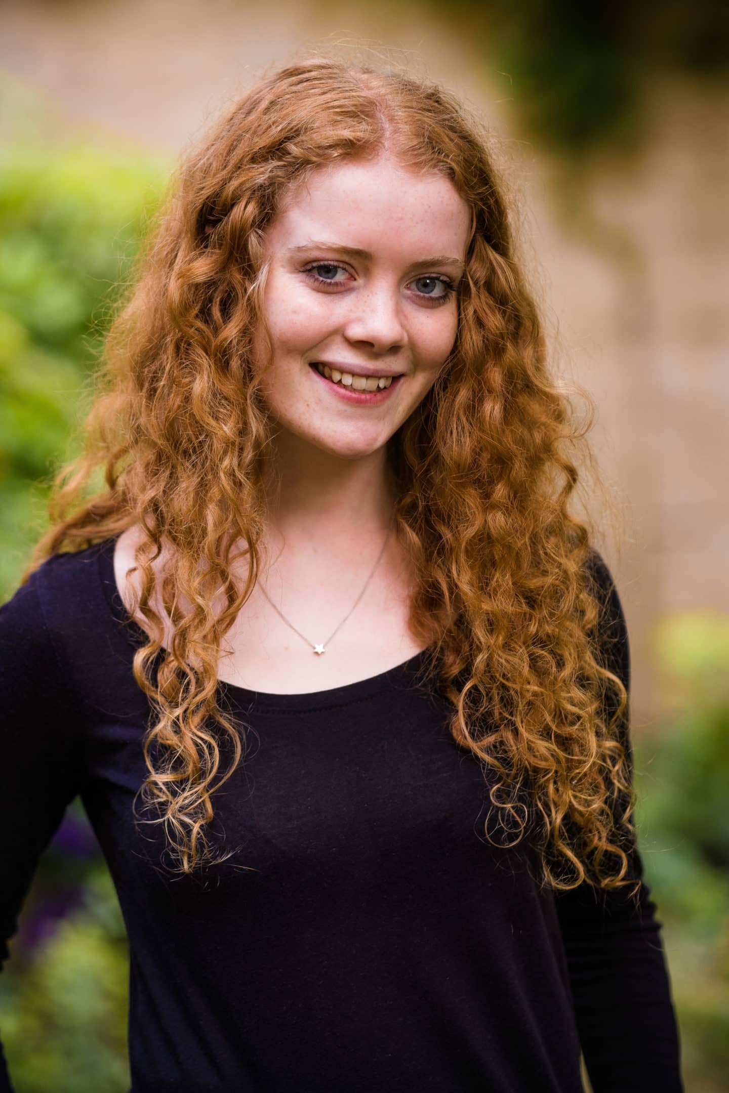 Headshot of Rebekah Goodchild, a young woman in a dark top and wearing a necklace with a star pendant