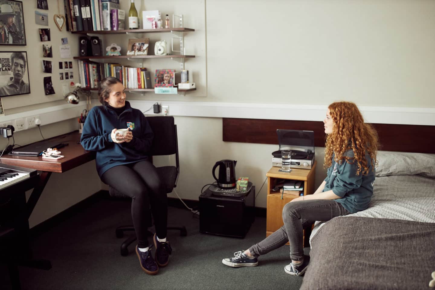 Two students sitting and talking in a bedroom