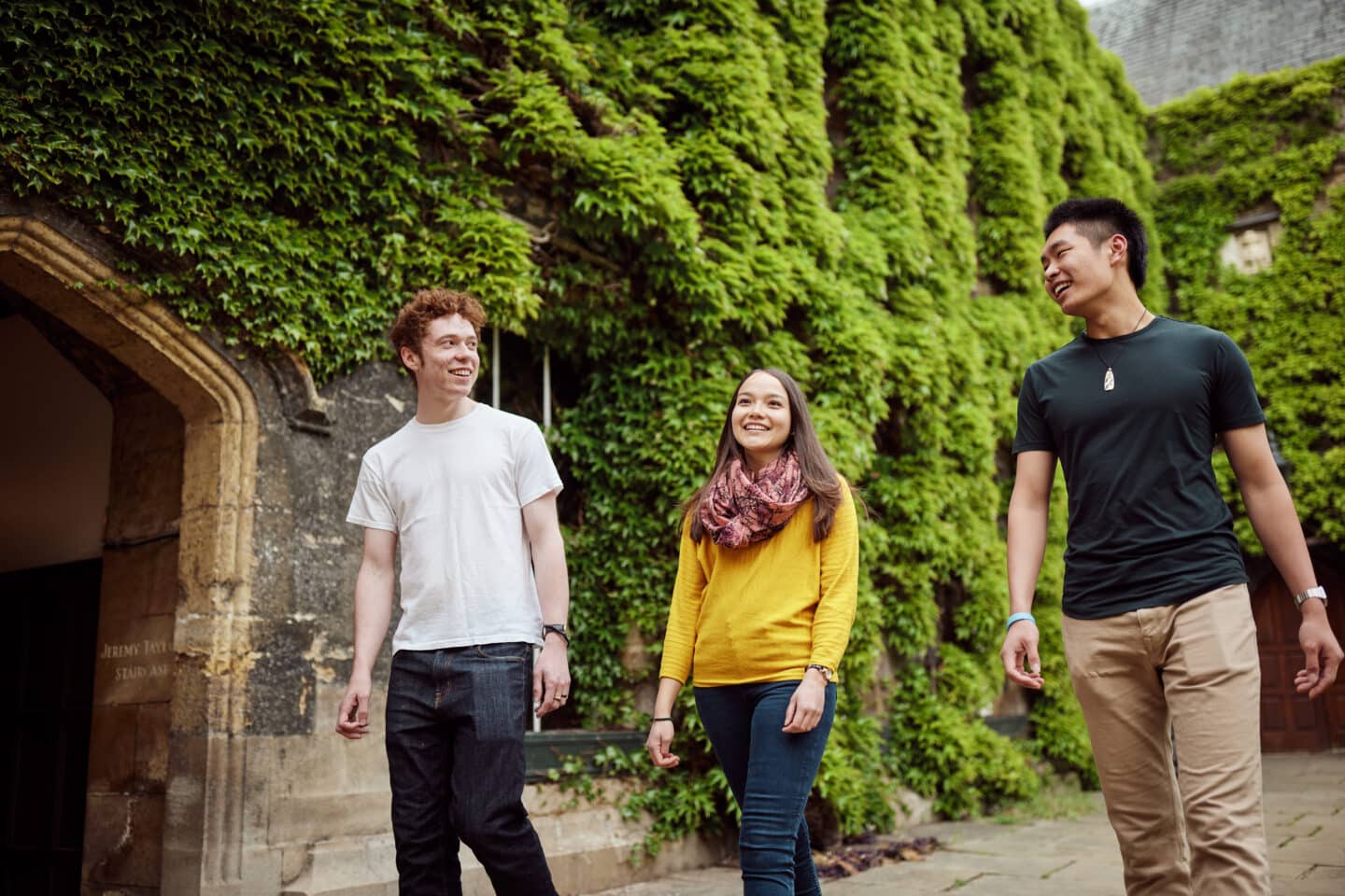 Photograph of three smiling students walking through a Lincoln College quad