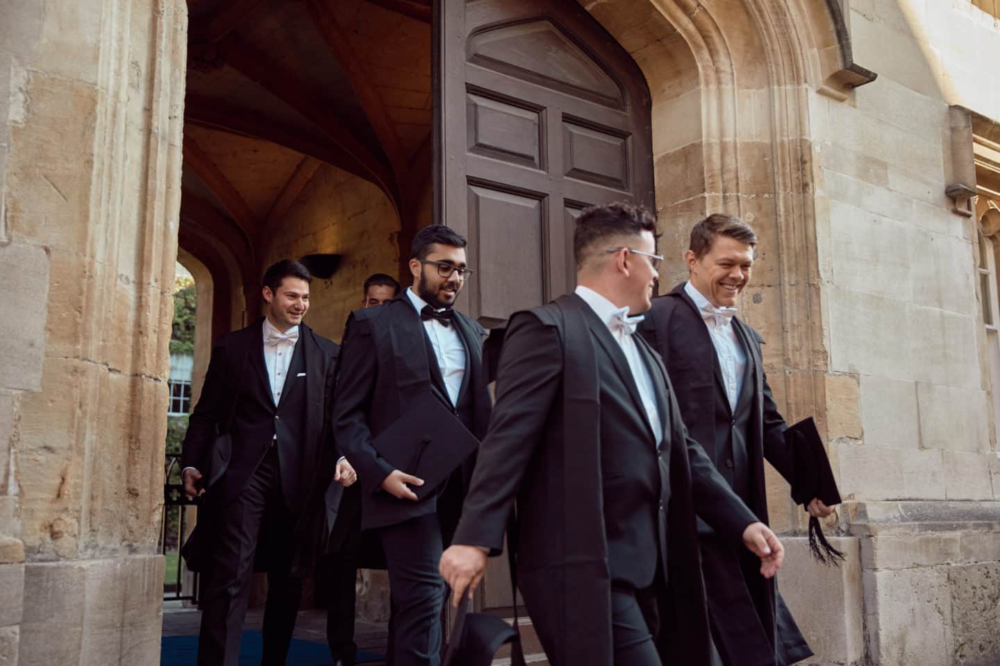 Students in white tie subfusc walking out of the front doors of Lincoln College