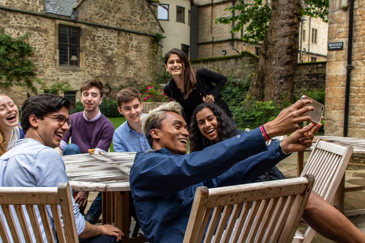 A group of students around a table in Lincoln College's Grove Quad, taking a group selfie