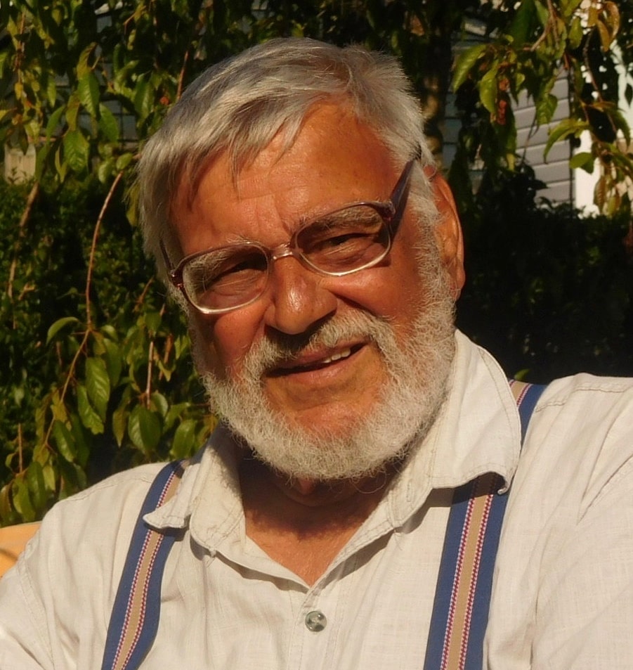 Headshot of Tony Bareham, a smiling man in glasses, wearing a white shirt with striped suspenders